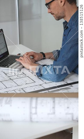Architect drawing and measuring blueprints on a desk, creating detailed floor plans and designs for construction projects, demonstrating precision and expertise in architectural planning Architect drawing and measuring blueprints on a desk, creating detailed floor plans and designs for construction projects, demonstrating precision and expertise in architectural planning 138515126