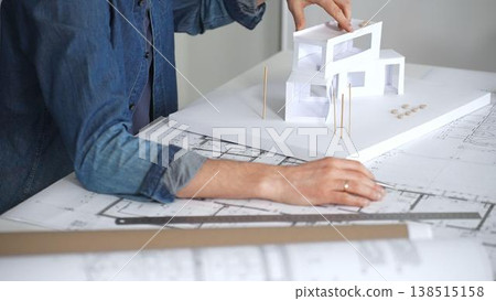 Architect hands reviewing building blueprints and housing plans on a table, utilizing a laptop for architectural drawing and design while planning a construction project Architect hands reviewing building blueprints and housing plans on a table, utilizing a laptop for architectural drawing and design while planning a construction project 138515158