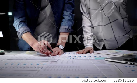 Collaboration of business professionals analyzing financial charts and data on papers and tablet, working late on a new strategy for company success Collaboration of business professionals analyzing financial charts and data on papers and tablet, working late on a new strategy for company success 138515159