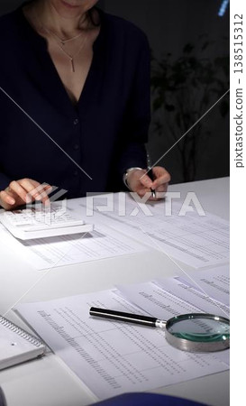 Woman working late night, calculating expense reports, reviewing financial documents with focused attention. Audit and taxes in business Woman working late night, calculating expense reports, reviewing financial documents with focused attention. Audit and taxes in business 138515312