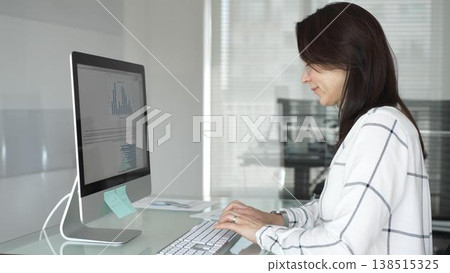 Woman working on desktop computer at office desk, typing and analyzing data, focusing on business tasks and professional work. Businesspeople concept Woman working on desktop computer at office desk, typing and analyzing data, focusing on business tasks and professional work. Businesspeople concept 138515325