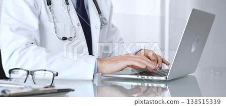 Doctor man typing on a laptop, providing online consultation and healthcare services, modern medical technology. Medicine, healthcare and science concept 138515339