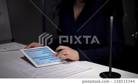 Businesswoman analyzing corporate financial data on a digital tablet in a dimly lit office, managing projects. Audit and taxes in business 138515344
