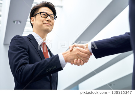 Businessmen exchanging smiles and handshakes: A business image of trust and partnership. Businessmen exchanging smiles and handshakes: A business image of trust and partnership. 138515347