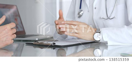 Doctor discussing medical information with patient during consultation, showing healthcare advice and diagnostic data on laptop. Medicine, healthcare and science concept 138515359