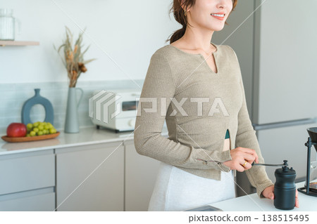 一位亞洲女性正在自家廚房用咖啡研磨機研磨咖啡豆。 138515495