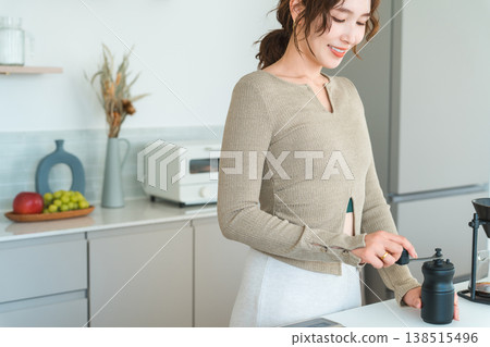 一位亞洲女性正在自家廚房用咖啡研磨機研磨咖啡豆。 一位亞洲女性正在自家廚房用咖啡研磨機研磨咖啡豆。 138515496