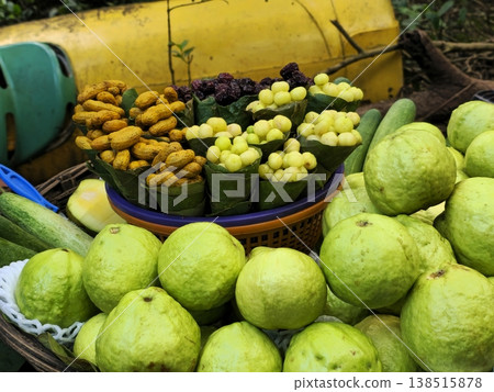 Close-up view of guava, amla, groundnuts, and mango pieces arranged in baskets at a roadside fruit vendor in a hill station market. Close-up view of guava, amla, groundnuts, and mango pieces arranged in baskets at a roadside fruit vendor in a hill station market. 138515878