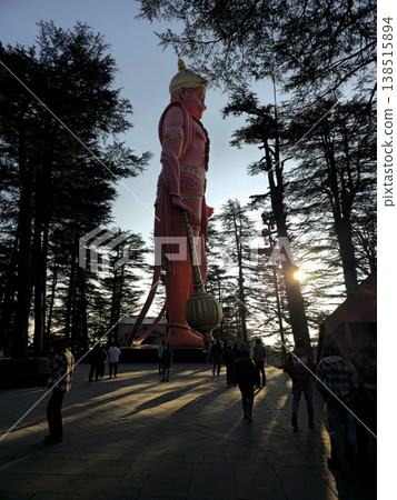 Massive Hanuman statue at Jakhu Temple rising above visitors, surrounded by forested hills, long shadows, and a spiritual atmosphere at sunset. Massive Hanuman statue at Jakhu Temple rising above visitors, surrounded by forested hills, long shadows, and a spiritual atmosphere at sunset. 138515894