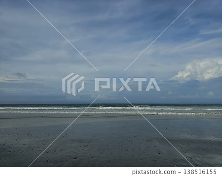Serene landscape view of an empty Andaman beach featuring wet, reflective sand and gentle rolling waves under a calm, cloudy sky. Serene landscape view of an empty Andaman beach featuring wet, reflective sand and gentle rolling waves under a calm, cloudy sky. 138516155