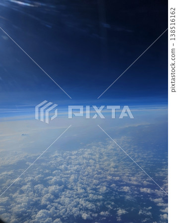 High-altitude aerial shot from a flight over Andaman, revealing the earth's atmosphere transitioning from deep blue to scattered white clouds below. High-altitude aerial shot from a flight over Andaman, revealing the earth's atmosphere transitioning from deep blue to scattered white clouds below. 138516162