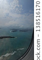 Vertical airplane window view capturing the edge of the aircraft overlooking scattered tropical islands in the Andaman Sea under cloudy skies. 138516170