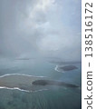 Dramatic overcast aerial shot looking down at dark landmasses and shallow turquoise reefs of the Andaman and Nicobar Islands scattered in the sea. 138516172