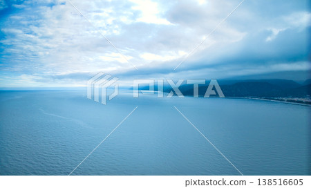 A view from the mouth of a small stream in eastern Toyama Prefecture in early spring, showing the Northern Alps and offshore wind turbines hidden by clouds. A view from the mouth of a small stream in eastern Toyama Prefecture in early spring, showing the Northern Alps and offshore wind turbines hidden by clouds. 138516605