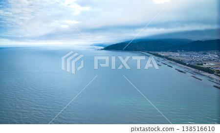 A view from the mouth of a small stream in eastern Toyama Prefecture in early spring, showing the Northern Alps and offshore wind turbines hidden by clouds. A view from the mouth of a small stream in eastern Toyama Prefecture in early spring, showing the Northern Alps and offshore wind turbines hidden by clouds. 138516610