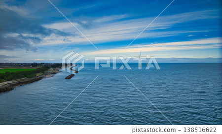 A view from the mouth of a small stream in eastern Toyama Prefecture in early spring, showing the Northern Alps and offshore wind turbines hidden by clouds. A view from the mouth of a small stream in eastern Toyama Prefecture in early spring, showing the Northern Alps and offshore wind turbines hidden by clouds. 138516622