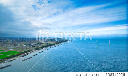 A view from the mouth of a small stream in eastern Toyama Prefecture in early spring, showing the Northern Alps and offshore wind turbines hidden by clouds. A view from the mouth of a small stream in eastern Toyama Prefecture in early spring, showing the Northern Alps and offshore wind turbines hidden by clouds. 138516656