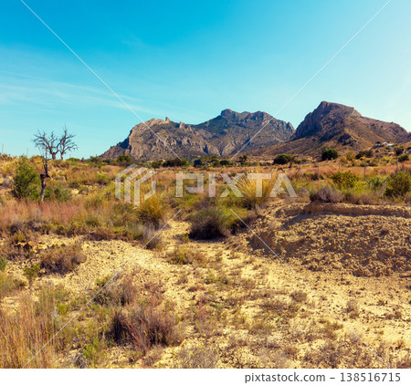 Panoramic view of mountain ridge and valley with dirt road on a sunny day 138516715