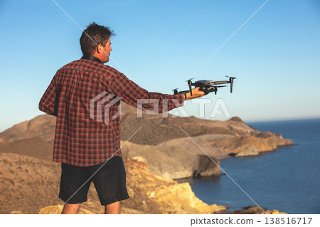 A male tourist launches a drone on a rocky beach. Seascape of Malaga, Spain A male tourist launches a drone on a rocky beach. Seascape of Malaga, Spain 138516717