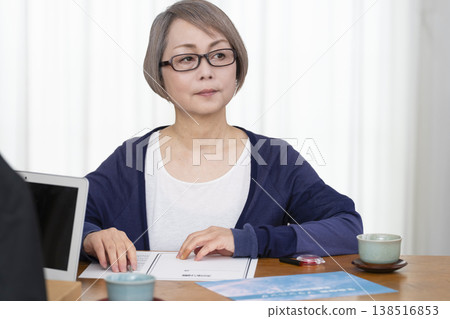 一位老年婦女簽署並蓋章了一份人壽保險契約。 一位老年婦女簽署並蓋章了一份人壽保險契約。 138516853