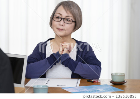 一位老年婦女簽署並蓋章了一份人壽保險契約。 一位老年婦女簽署並蓋章了一份人壽保險契約。 138516855