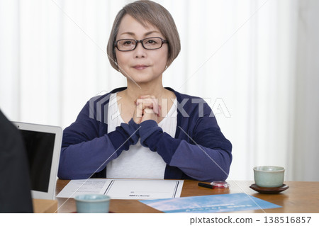一位老年婦女簽署並蓋章了一份人壽保險契約。 一位老年婦女簽署並蓋章了一份人壽保險契約。 138516857
