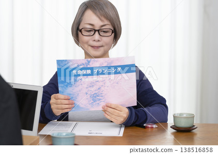 一位老年婦女簽署並蓋章了一份人壽保險契約。 一位老年婦女簽署並蓋章了一份人壽保險契約。 138516858