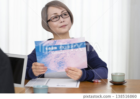 一位老年婦女簽署並蓋章了一份人壽保險契約。 一位老年婦女簽署並蓋章了一份人壽保險契約。 138516860