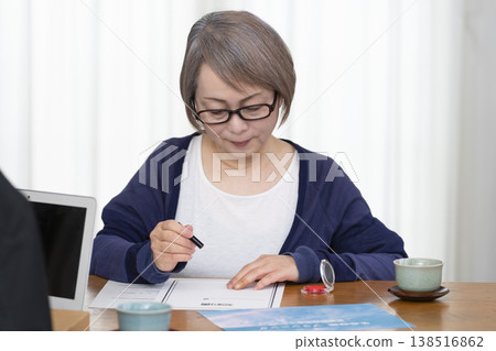 A senior woman signs and seals a life insurance contract. A senior woman signs and seals a life insurance contract. 138516862