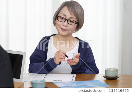 A senior woman signs and seals a life insurance contract. A senior woman signs and seals a life insurance contract. 138516865