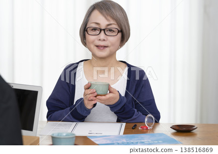 一位老年婦女簽署並蓋章了一份人壽保險契約。 一位老年婦女簽署並蓋章了一份人壽保險契約。 138516869