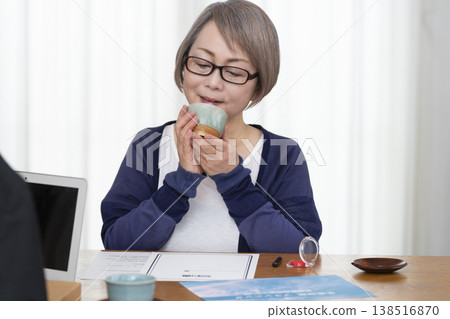 一位老年婦女簽署並蓋章了一份人壽保險契約。 一位老年婦女簽署並蓋章了一份人壽保險契約。 138516870