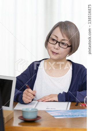 一位老年婦女簽署並蓋章了一份人壽保險契約。 一位老年婦女簽署並蓋章了一份人壽保險契約。 138516875