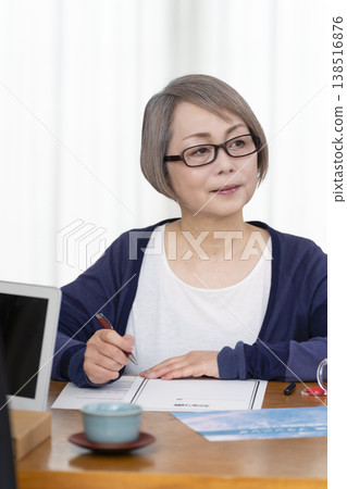 一位老年婦女簽署並蓋章了一份人壽保險契約。 一位老年婦女簽署並蓋章了一份人壽保險契約。 138516876