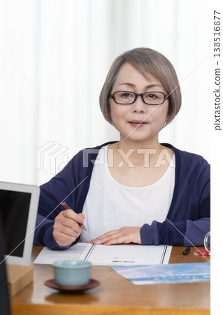 一位老年婦女簽署並蓋章了一份人壽保險契約。 一位老年婦女簽署並蓋章了一份人壽保險契約。 138516877