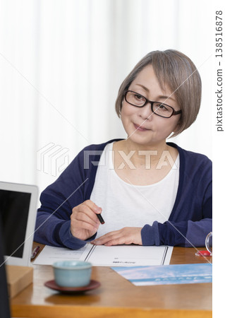 一位老年婦女簽署並蓋章了一份人壽保險契約。 一位老年婦女簽署並蓋章了一份人壽保險契約。 138516878
