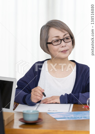 一位老年婦女簽署並蓋章了一份人壽保險契約。 一位老年婦女簽署並蓋章了一份人壽保險契約。 138516880