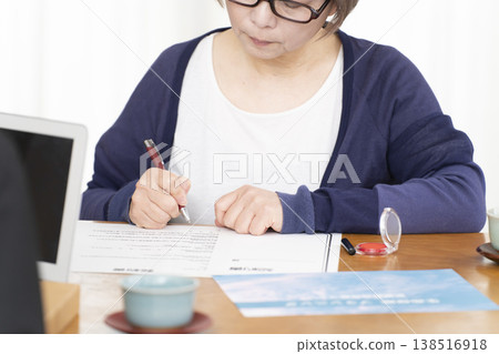 A senior woman's hands as she signs and seals a life insurance contract. A senior woman's hands as she signs and seals a life insurance contract. 138516918