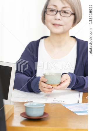 A senior woman's hands as she signs and seals a life insurance contract. A senior woman's hands as she signs and seals a life insurance contract. 138516932