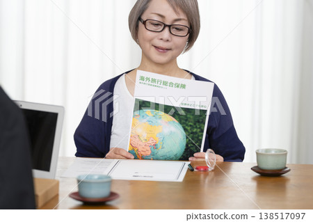 一位老年婦女簽署並蓋章了她的海外旅行保險合約。 一位老年婦女簽署並蓋章了她的海外旅行保險合約。 138517097