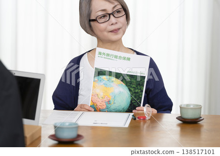 一位老年婦女簽署並蓋章了她的海外旅行保險合約。 一位老年婦女簽署並蓋章了她的海外旅行保險合約。 138517101