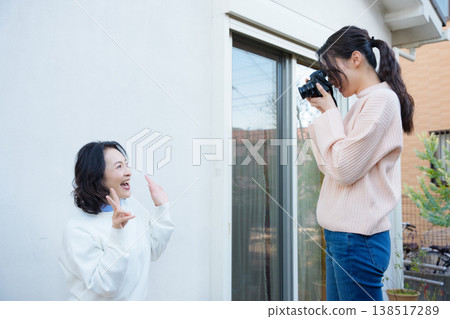 一幅母女關係親密的肖像畫,女兒正在陽台上為母親拍照。 一幅母女關係親密的肖像畫,女兒正在陽台上為母親拍照。 138517289