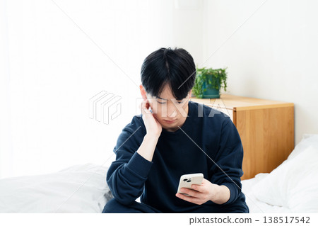 年輕人在床上觀看智能手機 138517542