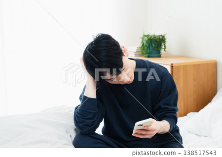 年輕人在床上觀看智能手機 138517543