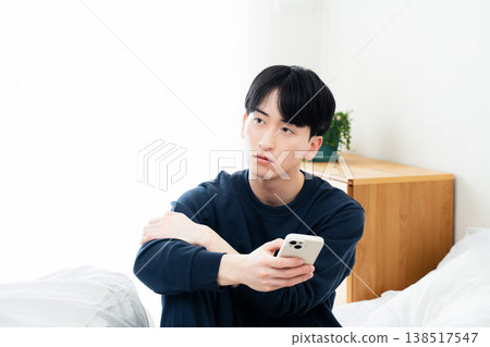 年輕人在床上觀看智能手機 138517547