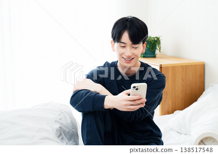 年輕人在床上觀看智能手機 138517548