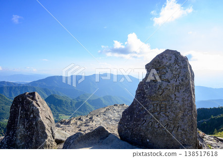 大賀桃山山頂紀念碑,美之原最高峰,以及雄偉的信州山脈在藍天下綿延展開。 大賀桃山山頂紀念碑,美之原最高峰,以及雄偉的信州山脈在藍天下綿延展開。 138517618