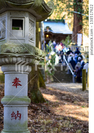 A stone lantern stands in the shrine grounds, and the scene of a bustling winter New Year's visit to a shrine is filled with worshippers. A stone lantern stands in the shrine grounds, and the scene of a bustling winter New Year's visit to a shrine is filled with worshippers. 138517622