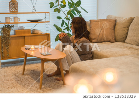 一位亞洲女性夜晚在客廳放鬆地啜飲著熱飲。 一位亞洲女性夜晚在客廳放鬆地啜飲著熱飲。 138518329