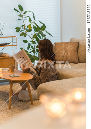 一位時尚的亞洲女性夜晚坐在客廳閱讀雜誌。 一位時尚的亞洲女性夜晚坐在客廳閱讀雜誌。 138518331